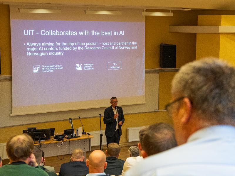 Dresskledd mann holder en presentasjon i et auditorium